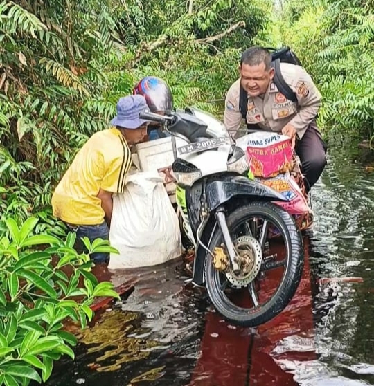 Bhabinkamtibmas di Tebingtinggi Timur Ini Bantu Warga Melintasi Jalan Terendam Banjir